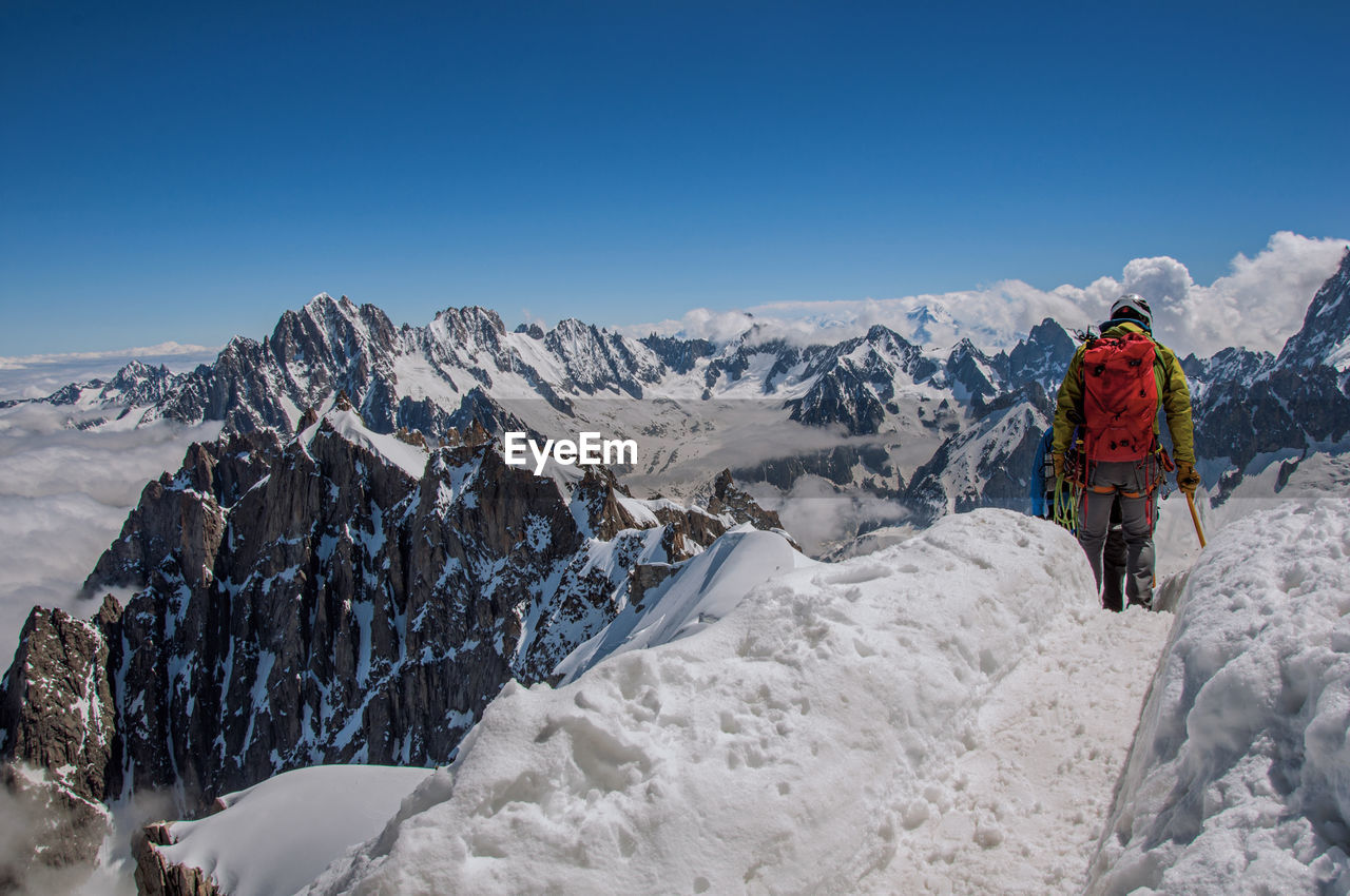 Climbers walking on snowy path in a sunny day at the aiguille du midi, near chamonix, france.