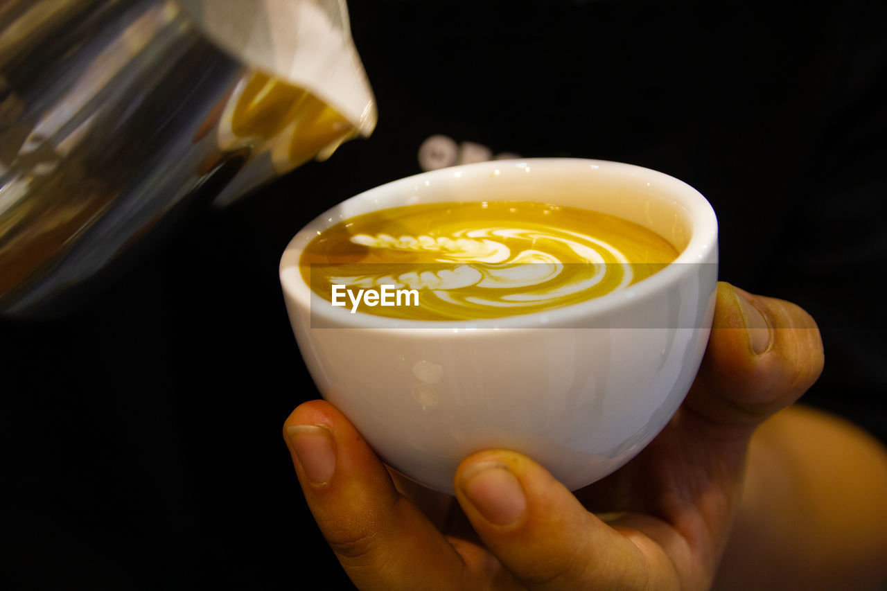 CLOSE-UP OF HAND HOLDING COFFEE