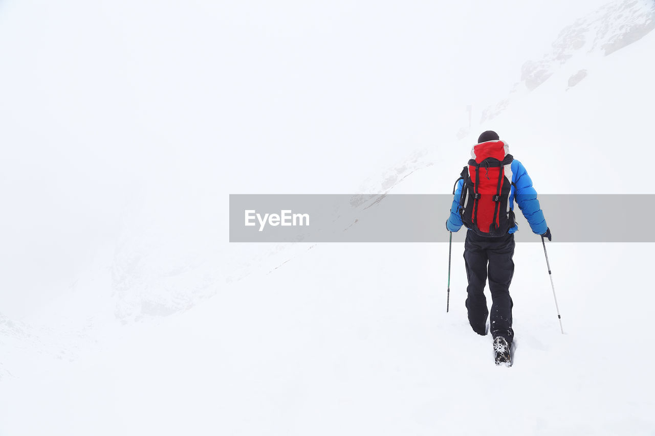 Rear view of man hiking in snow