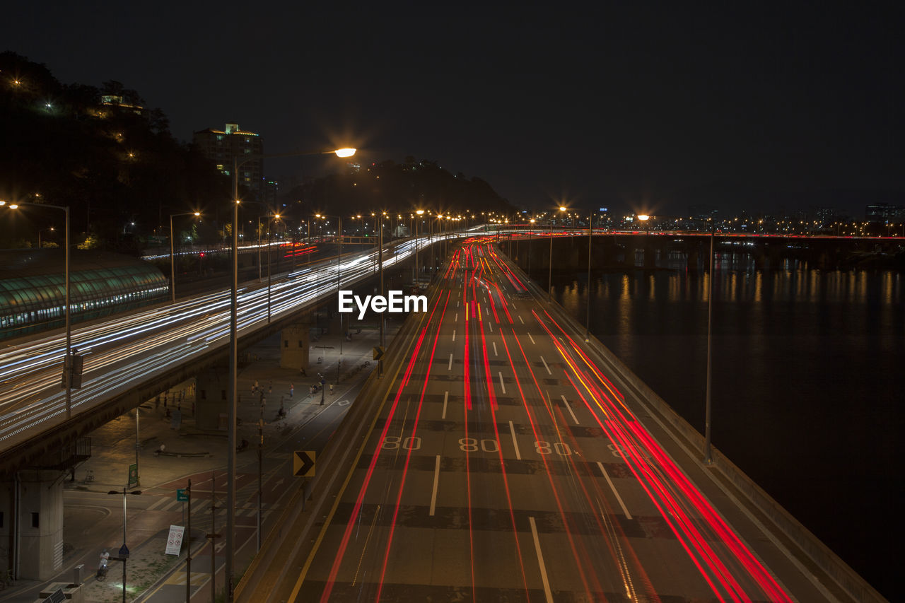 High angle view of light trails on bridge and street by river