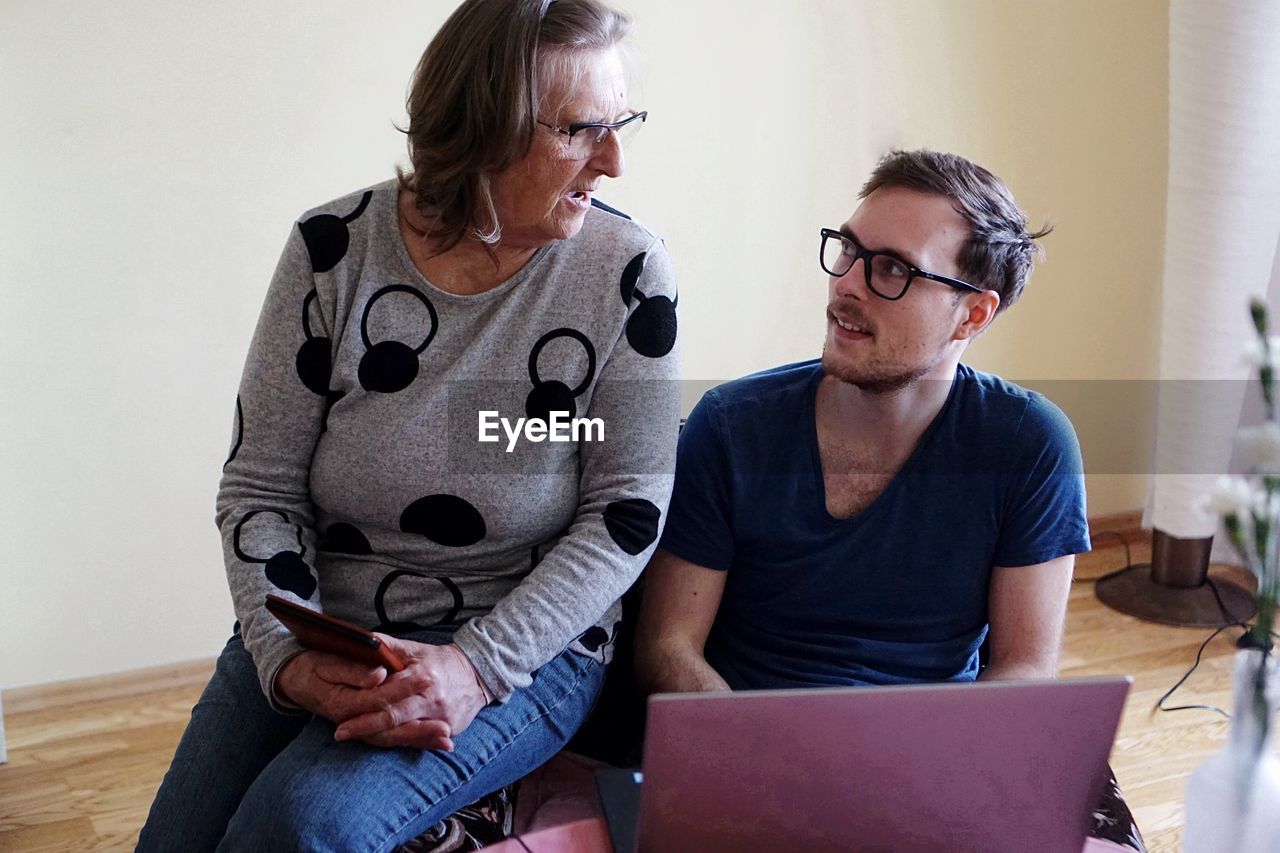 Mother and son talking while using laptop at home