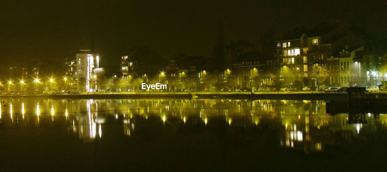 ILLUMINATED CITY BY RIVER AGAINST SKY