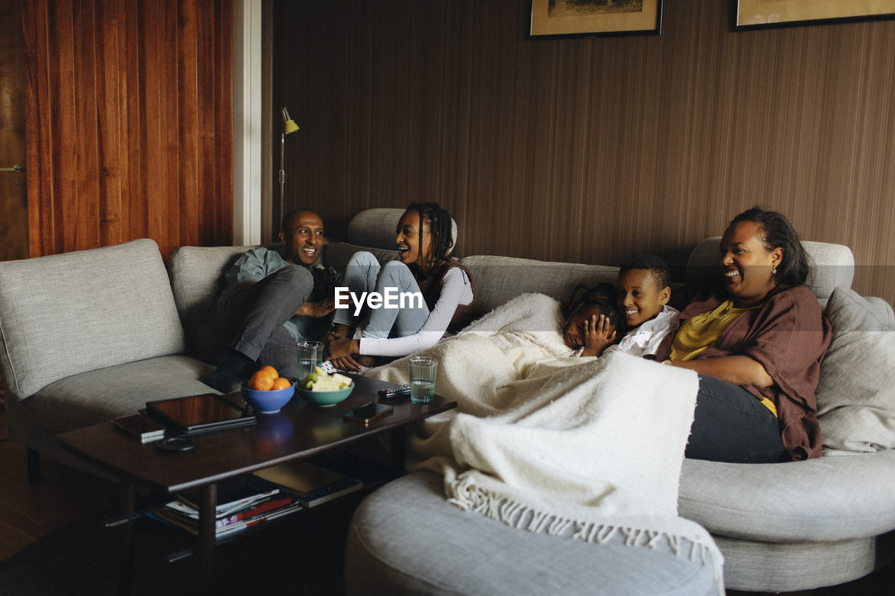 Happy family sitting together on sofa in living room at home