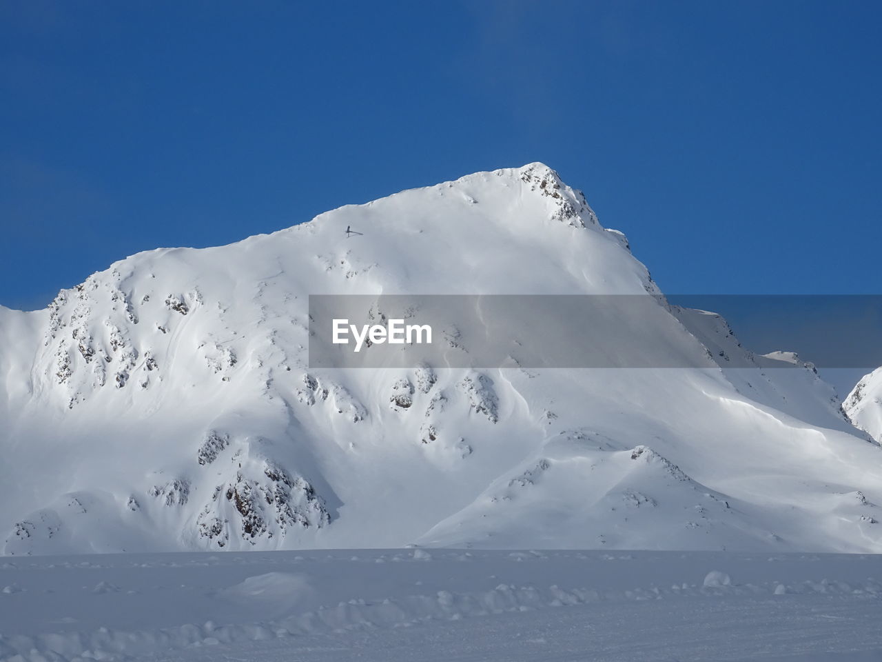 Low angle view of snowcapped mountain against blue sky