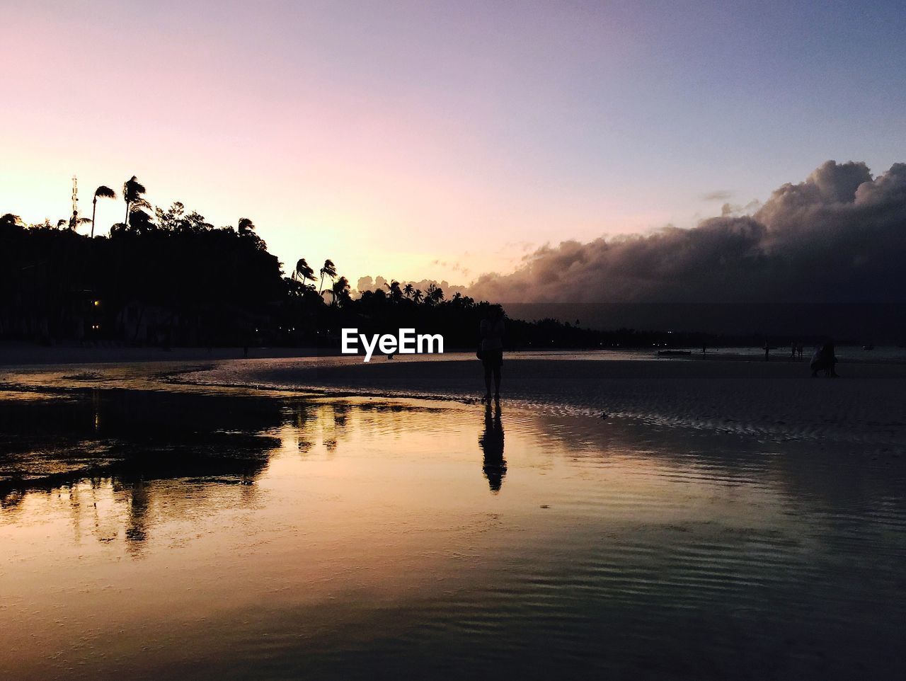 Reflection of person in water at beach during sunset