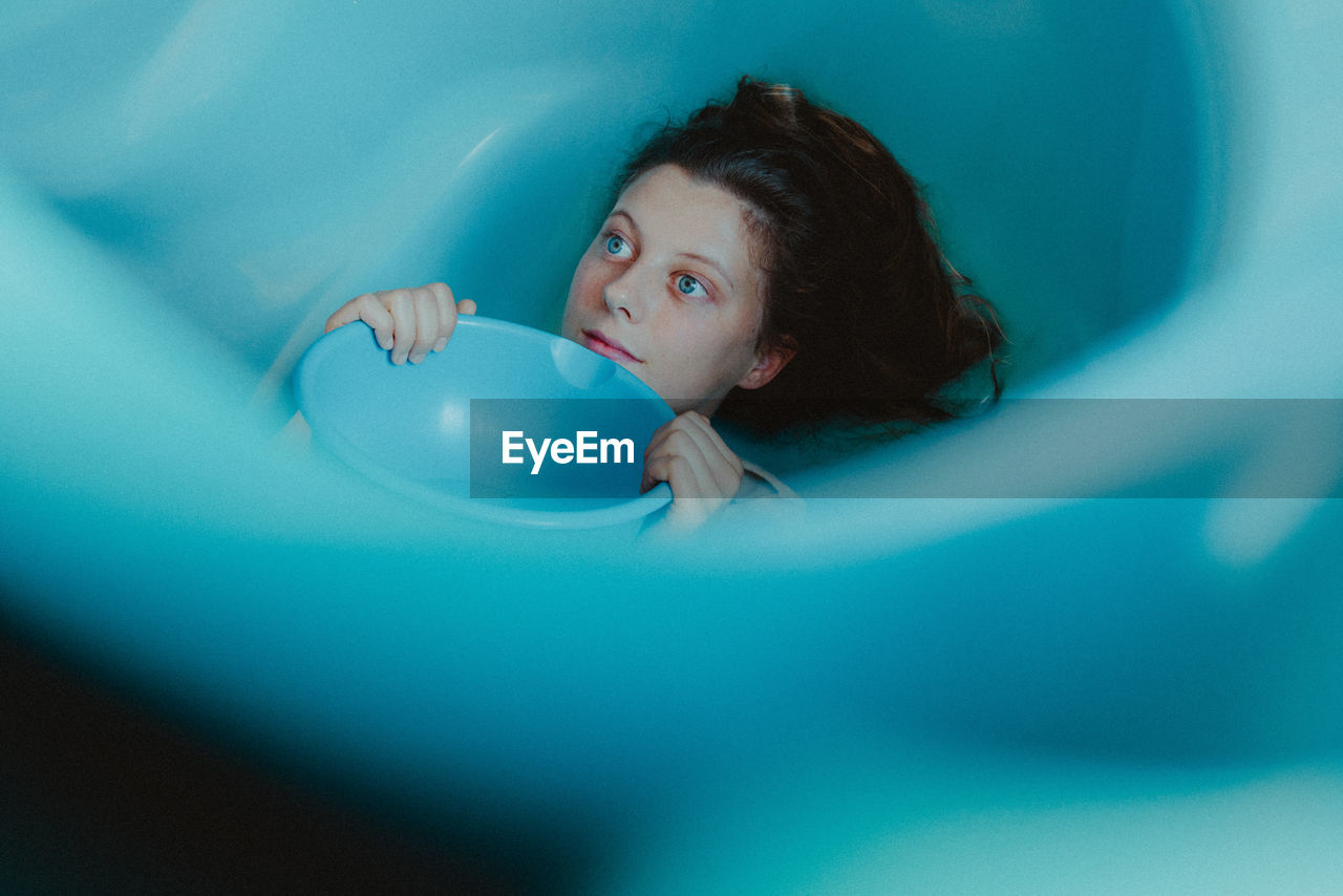 HIGH ANGLE VIEW PORTRAIT OF YOUNG WOMAN LYING DOWN IN BATHROOM