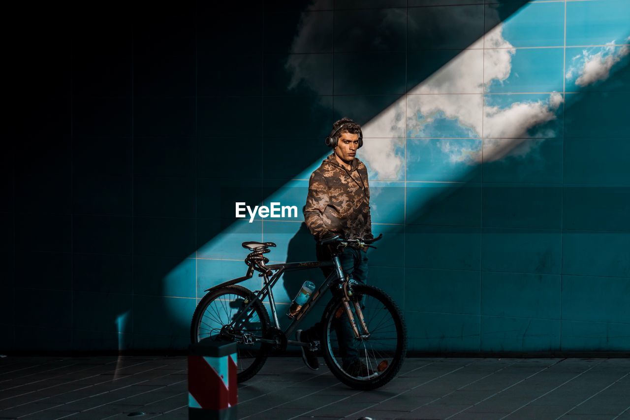 MAN RIDING BICYCLE BY WALL