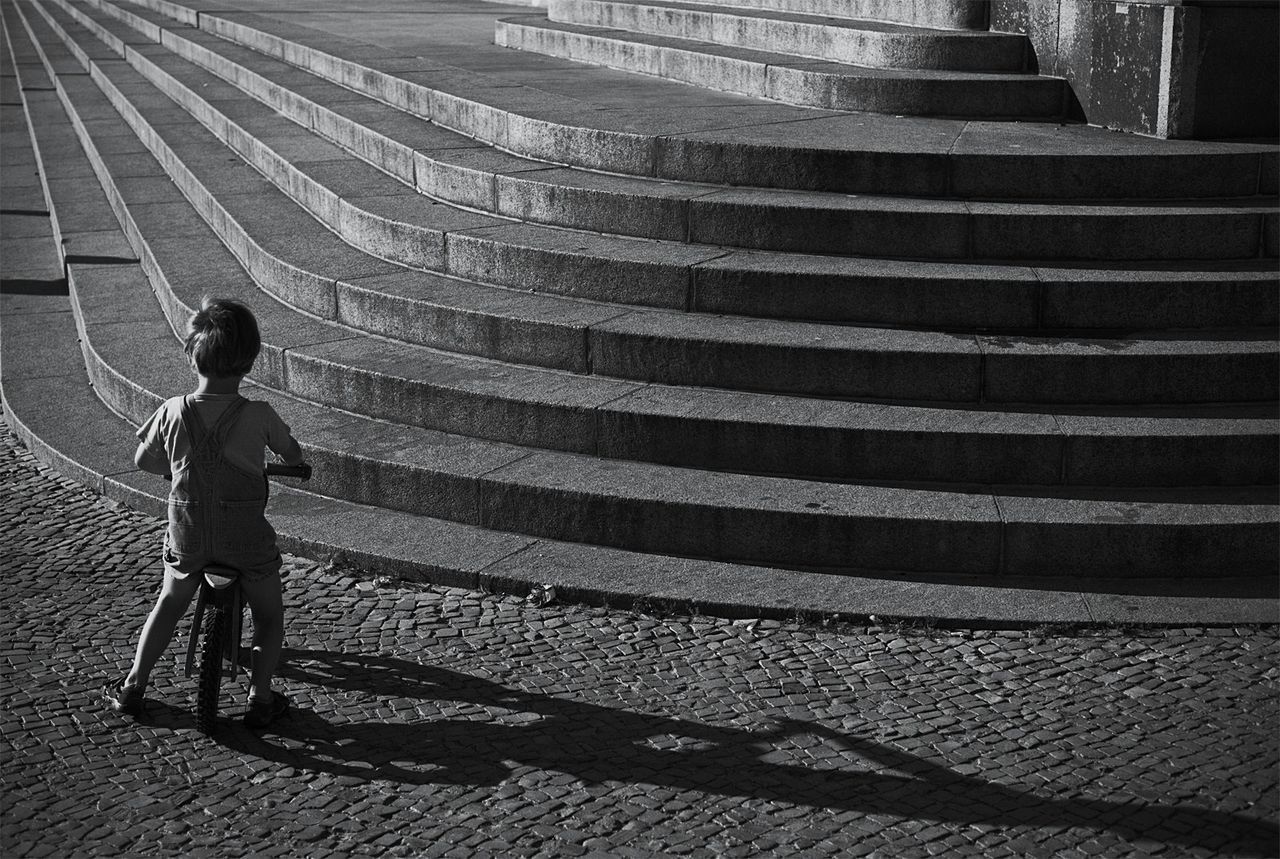 Rear view of boy on bicycle in front of concrete steps