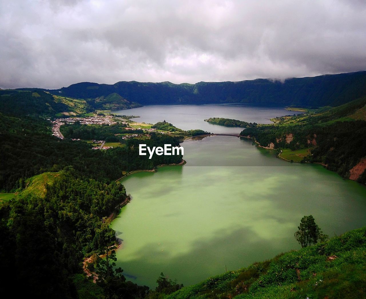 High angle view of lake against mountains and cloudy sky