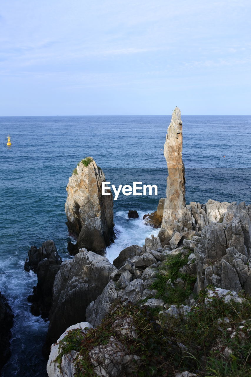 Rocks on sea shore against sky