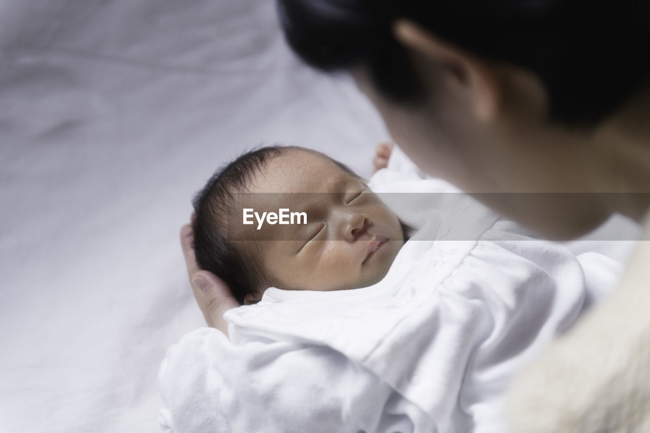 Close-up of mother holding newborn son on bed