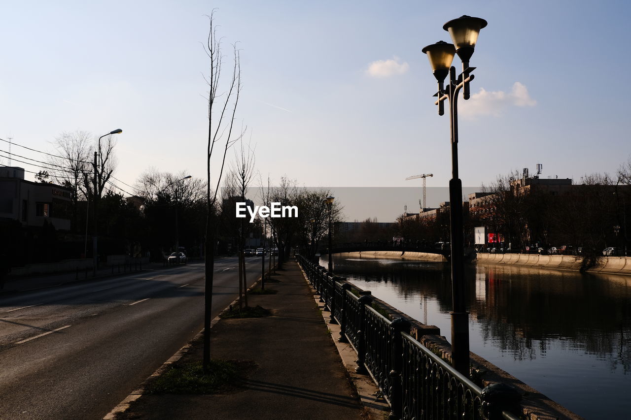 sky, evening, street light, reflection, street, water, nature, architecture, tree, city, transportation, dusk, no people, built structure, lighting equipment, plant, lighting, urban area, sunset, outdoors, road, waterway, building exterior, cloud, river, day, cityscape, clear sky