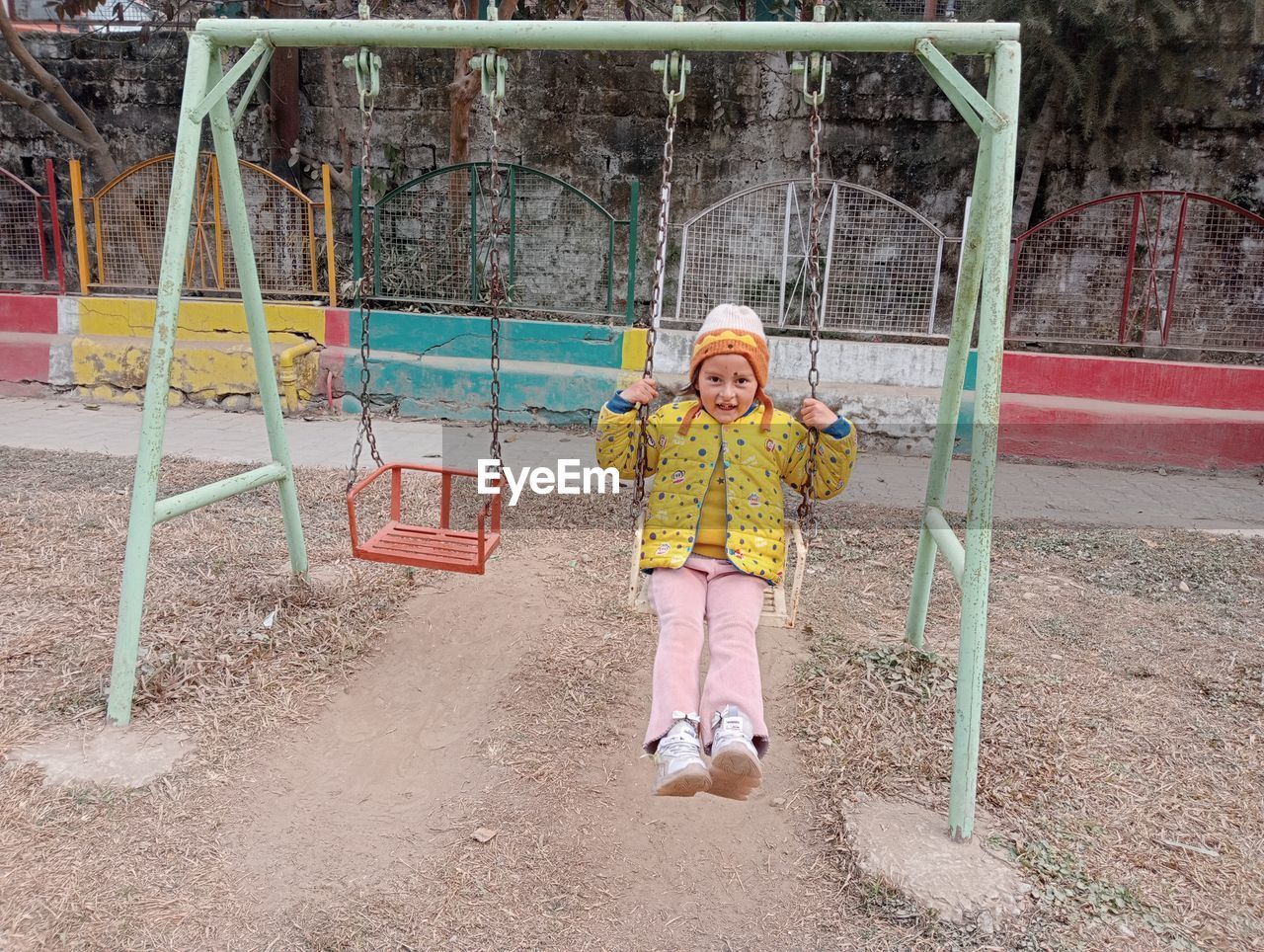 full length of boy swinging on swing at playground