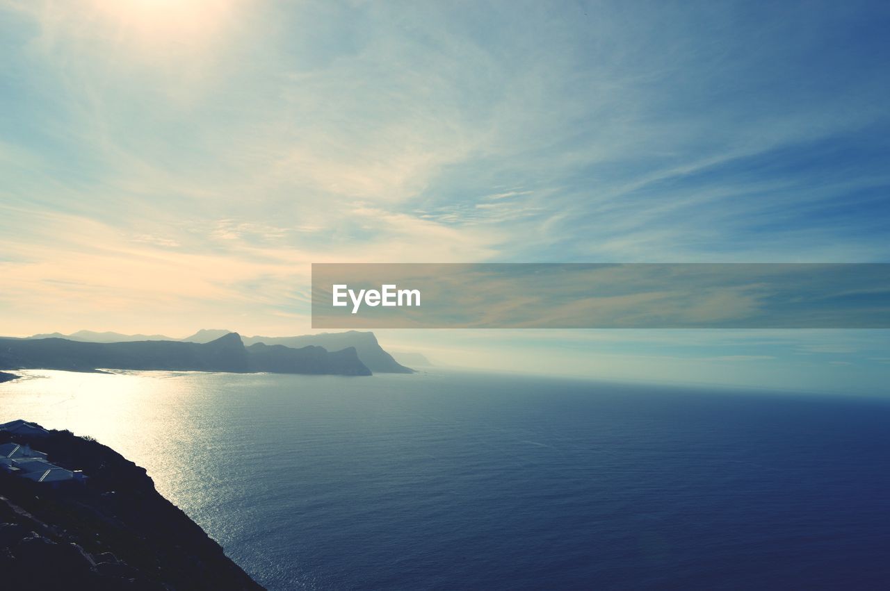 Scenic view of sea against cloudy sky on sunny day