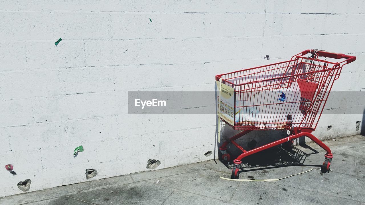 Side view of shopping trolley against white wall
