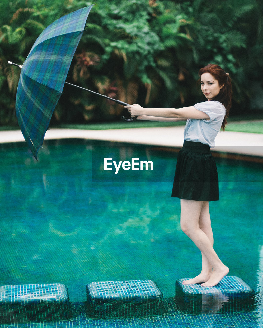 Young woman holding umbrella standing in water