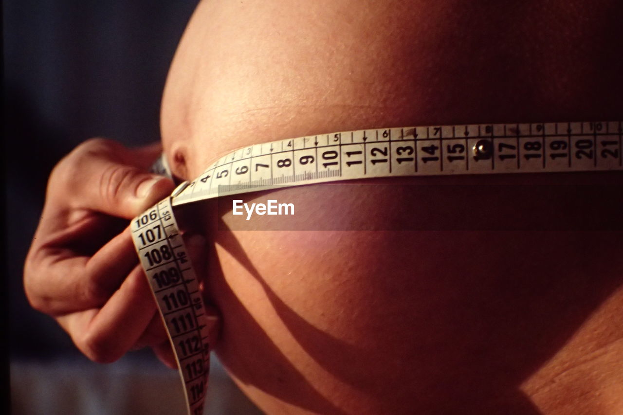 Midsection of pregnant woman measuring abdomen