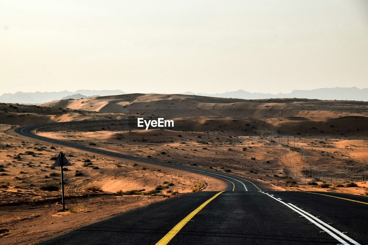 Road passing through desert against sky