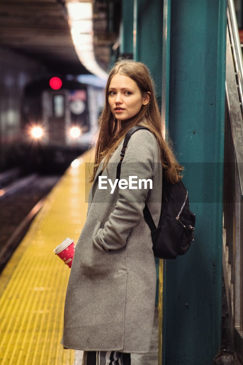 Beautiful young woman standing at subway station platform