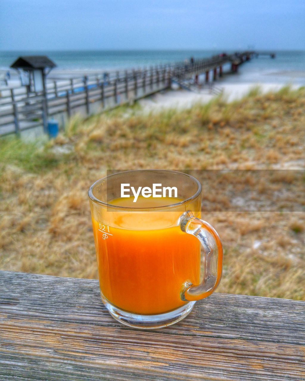 Glass of water on beach against sky