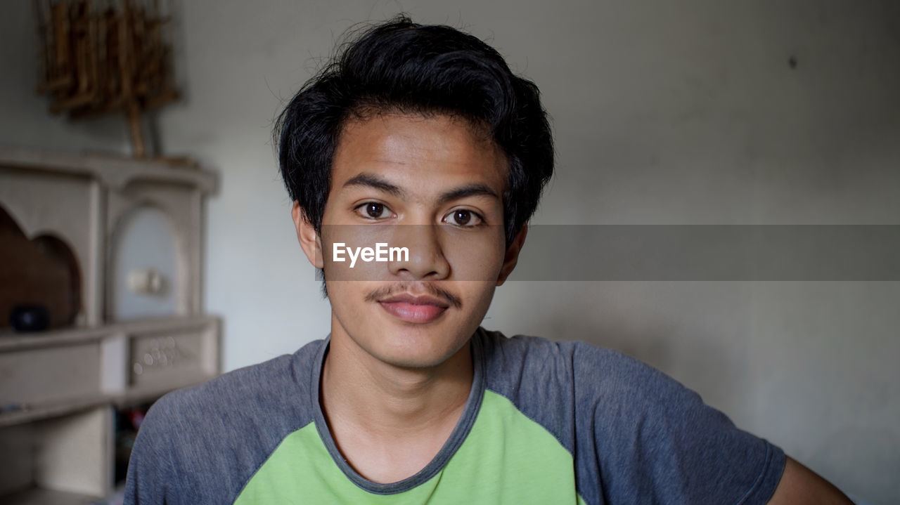 Portrait of young man against wall at home