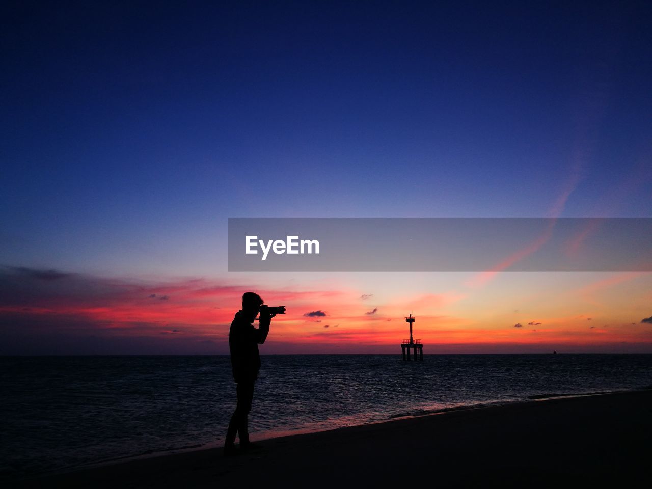 Silhouette man photographing against sky during sunset