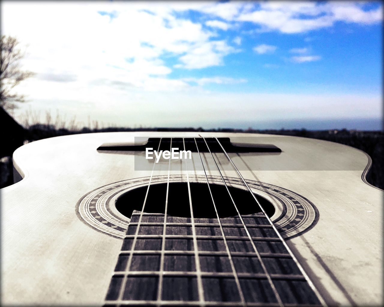 Close-up of acoustic guitar against blue sky