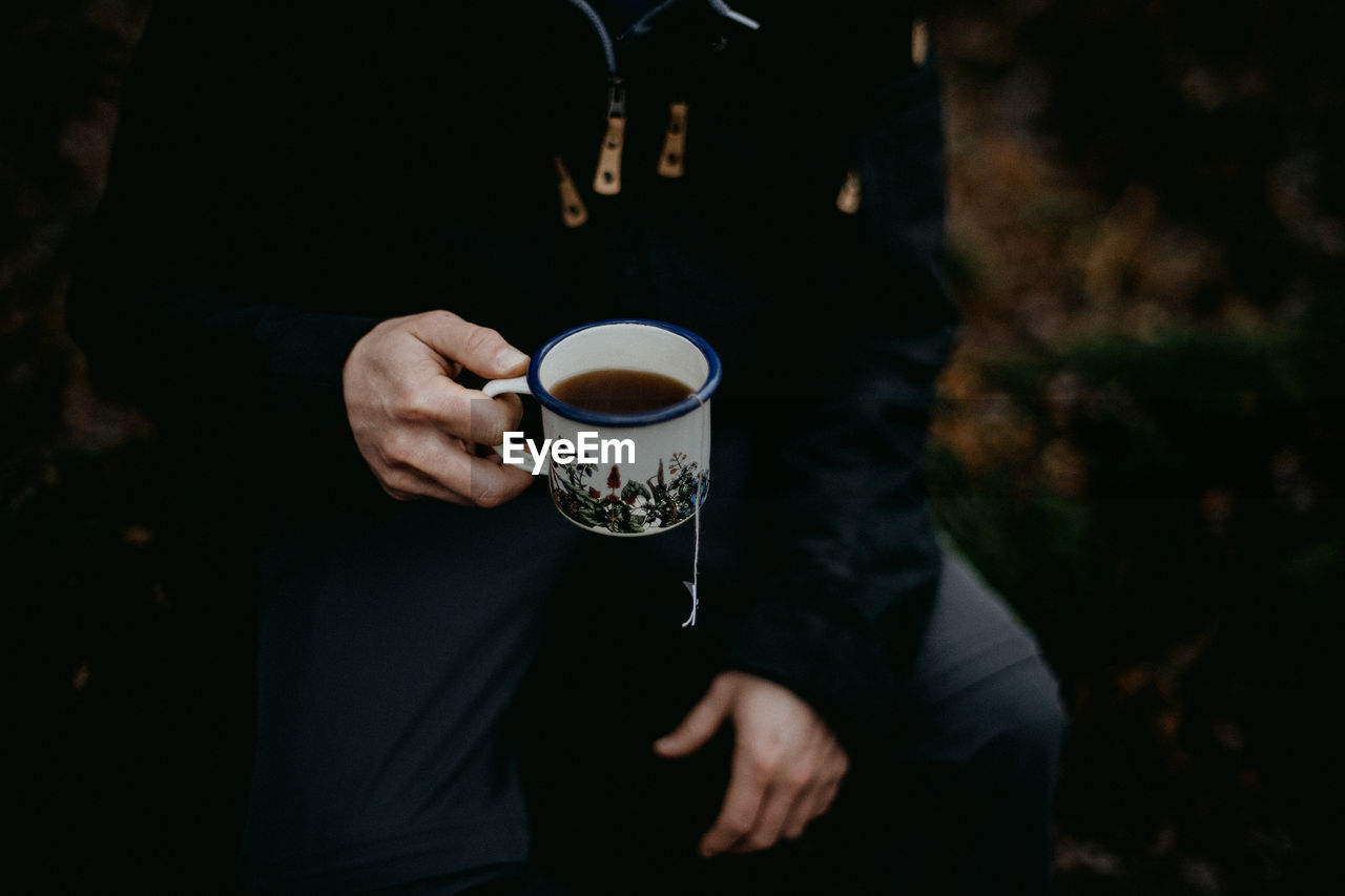 Man holding an enamel mug of tea