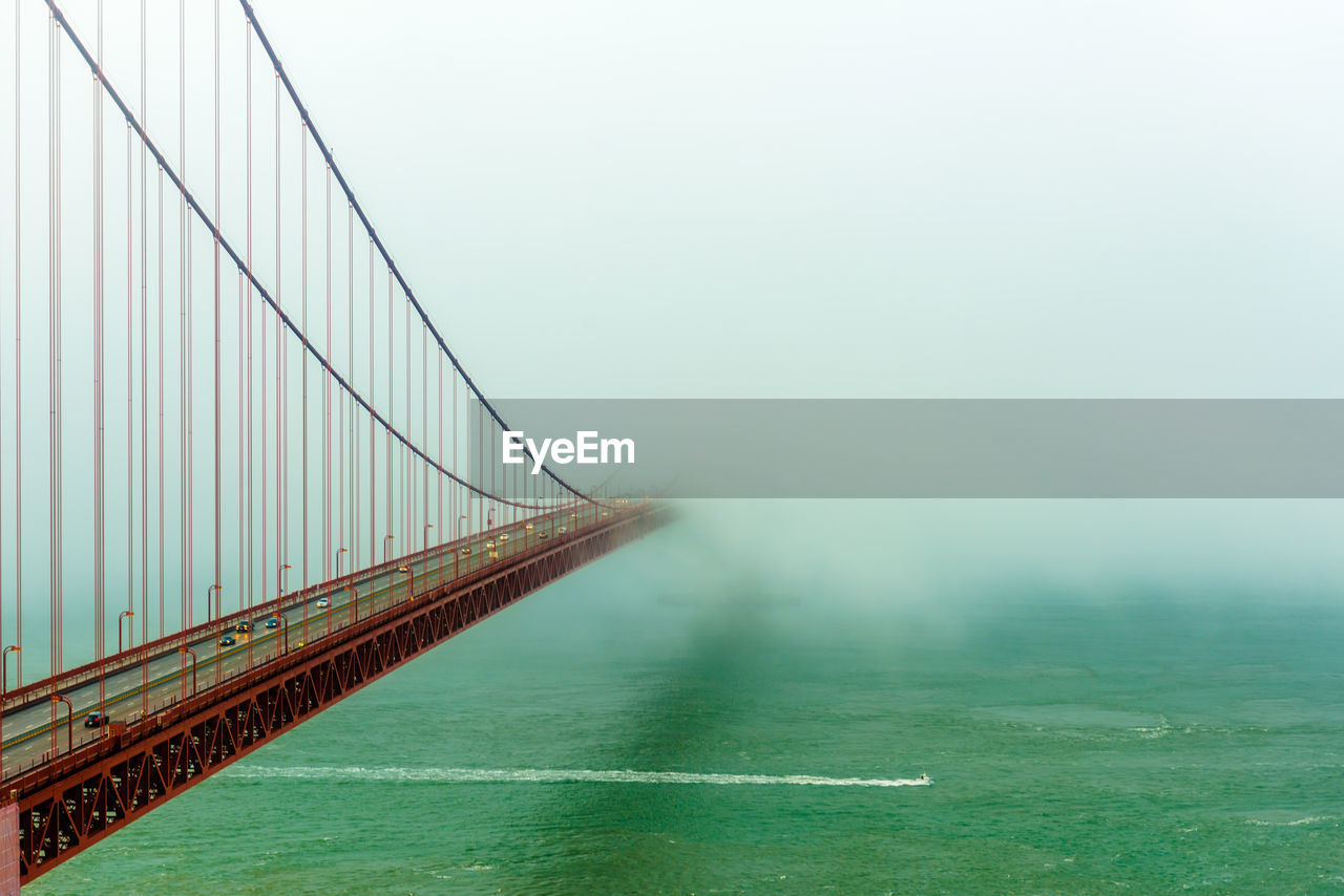 SUSPENSION BRIDGE IN SEA AGAINST SKY