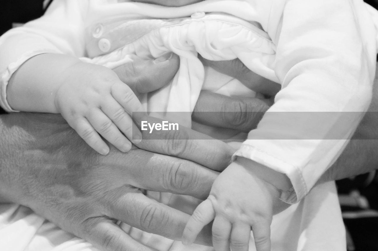 Cropped hands of mother holding baby