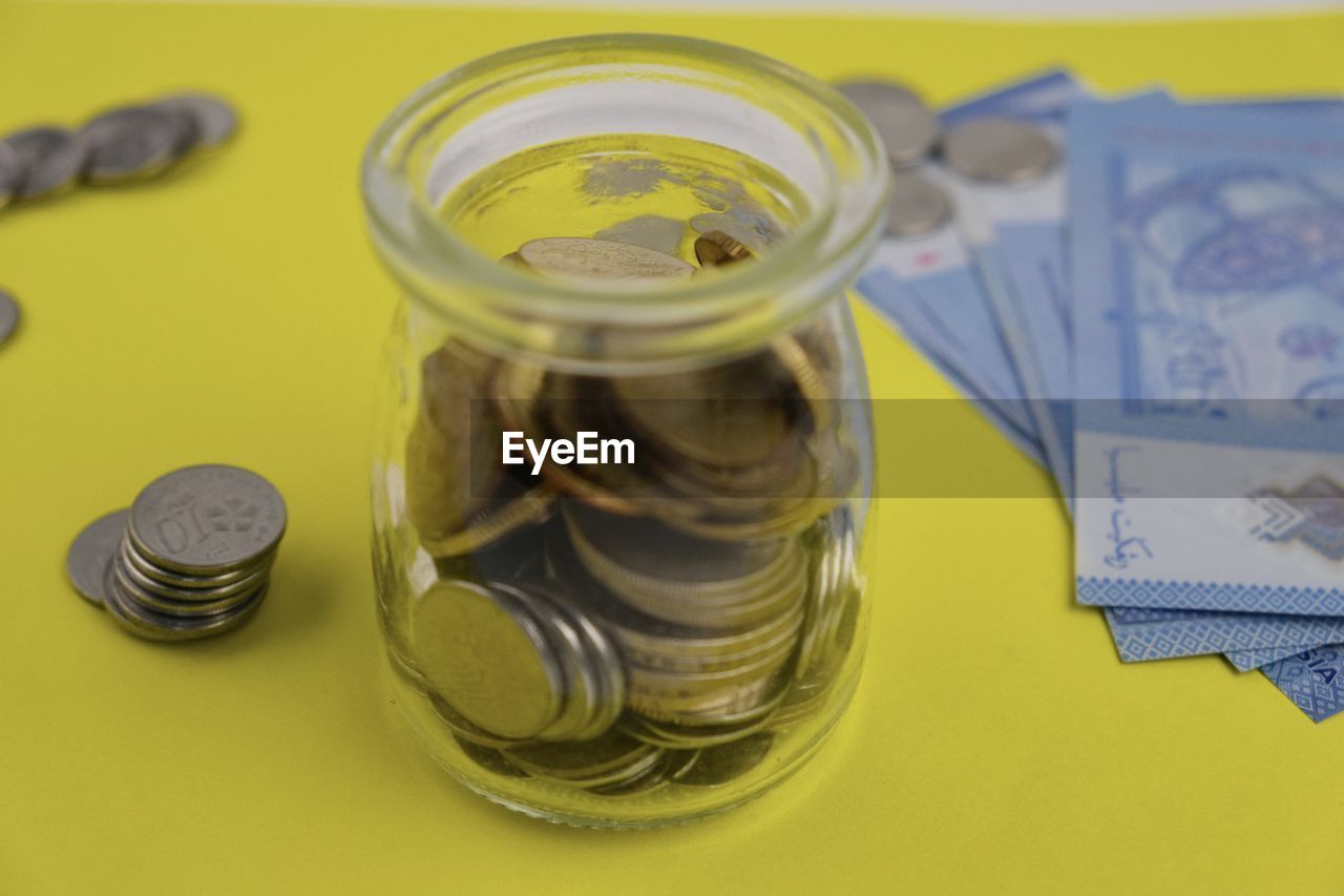 currency, finance, coin, money, savings, wealth, business, paper currency, investment, jar, finance and economy, economy, indoors, no people, close-up, exchange rate, colored background, studio shot, banking, container, high angle view, business finance and industry, home finances, cash, glass