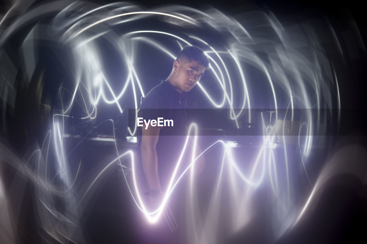 DIGITAL COMPOSITE IMAGE OF MAN WITH LIGHT PAINTING