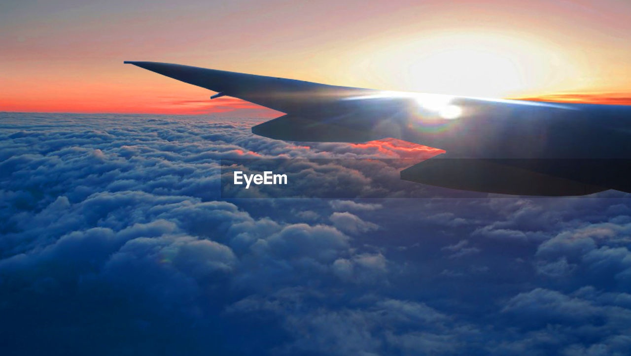 CROPPED IMAGE OF AIRPLANE WING OVER CLOUDS