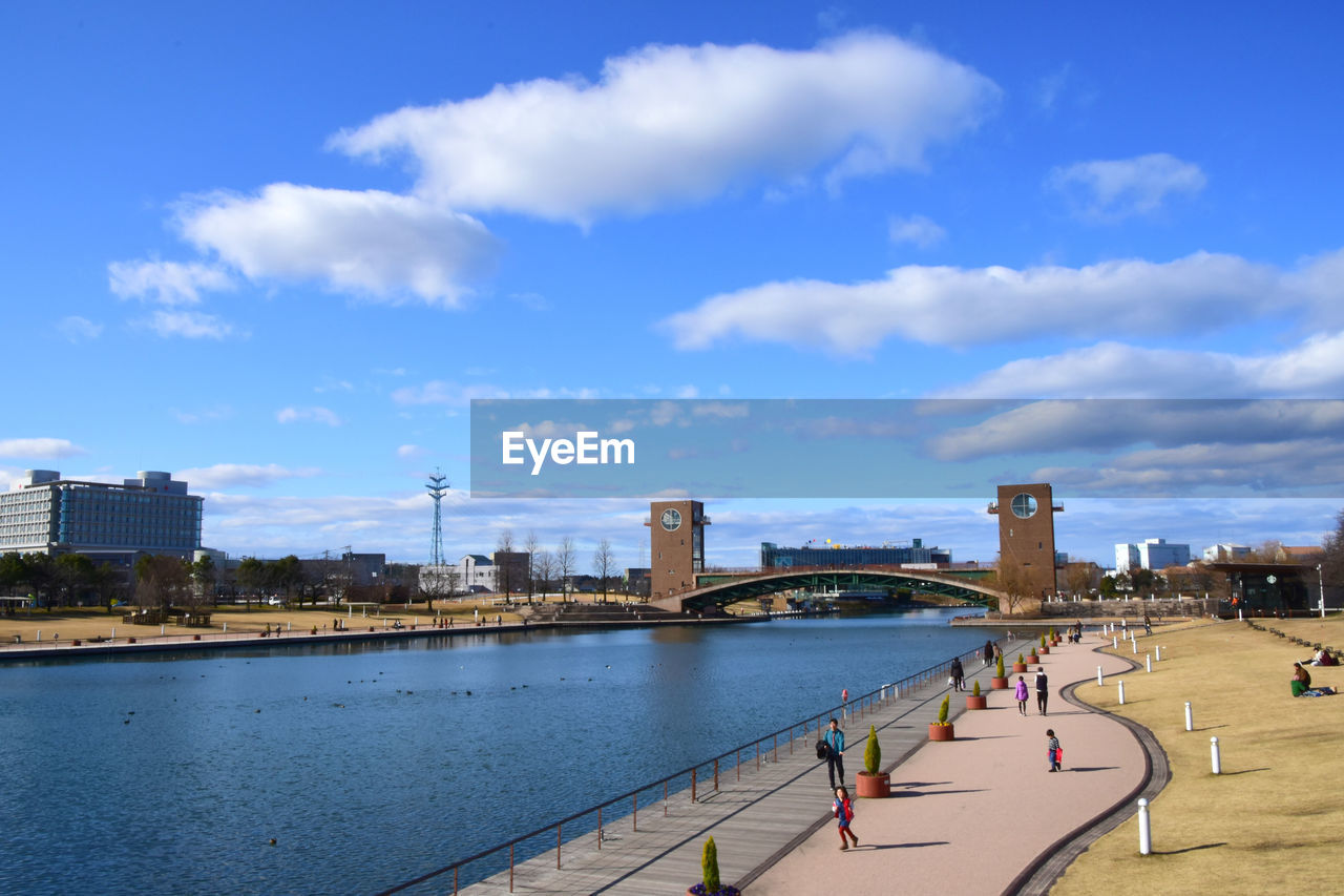 PEOPLE ON RIVER BY BUILDINGS AGAINST SKY