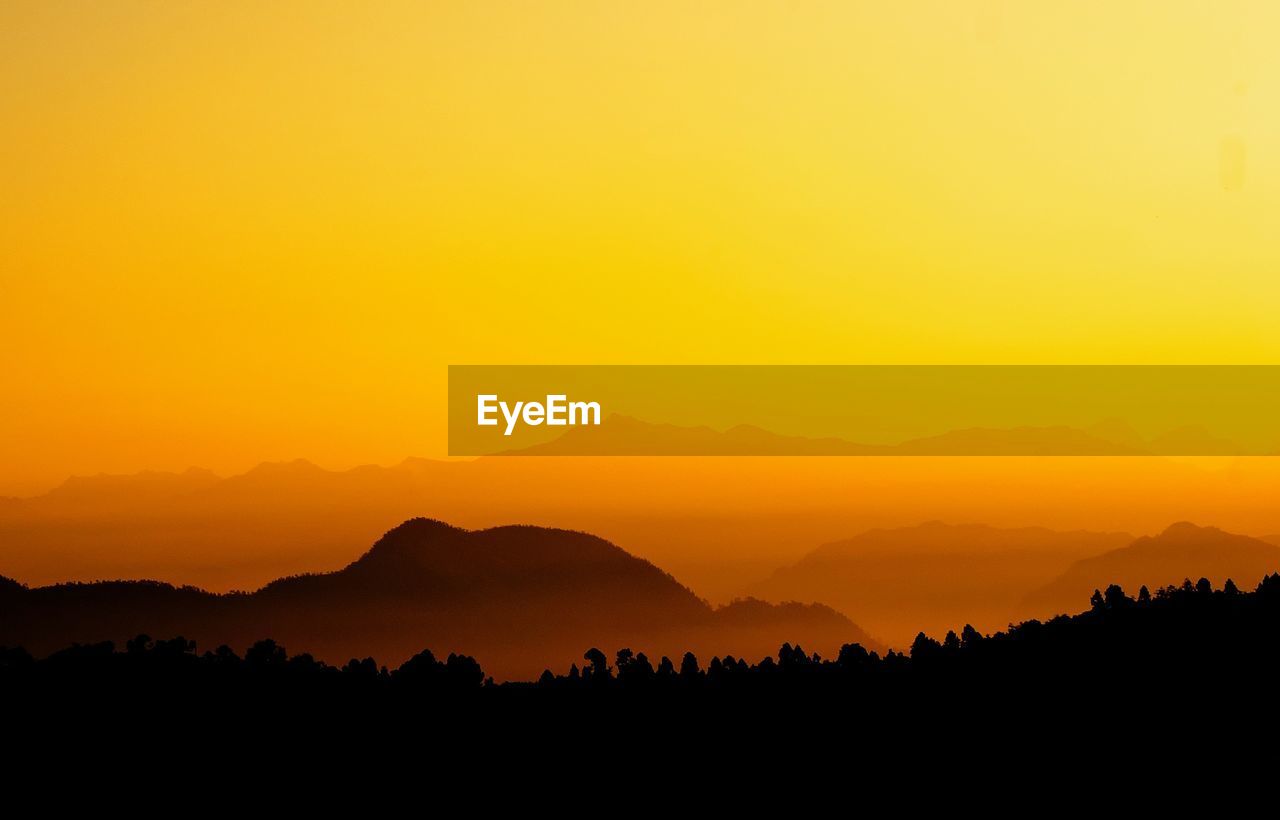 Scenic view of silhouette mountains against orange sky