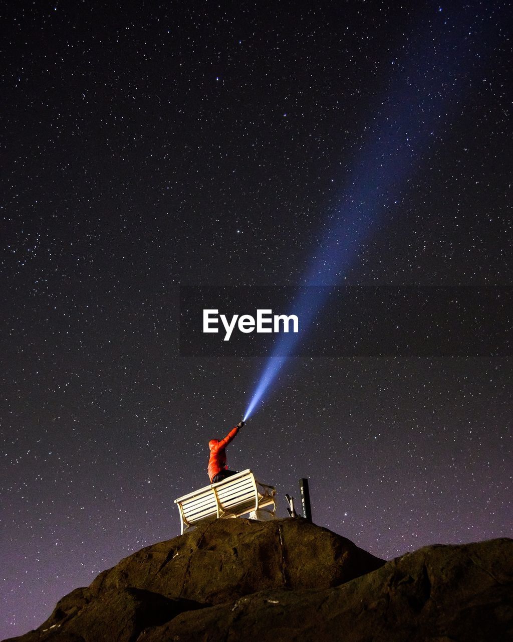 Low angle view of man with flashlight against sky at night