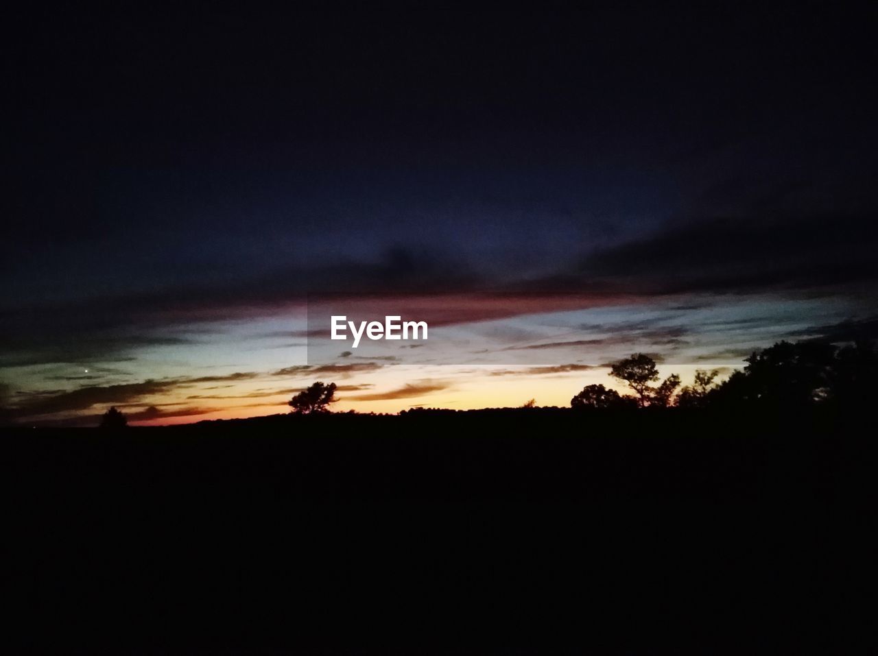 SILHOUETTE LANDSCAPE AGAINST DRAMATIC SKY AT SUNSET