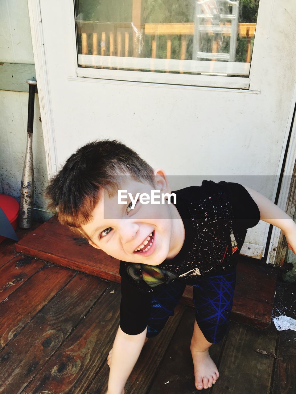 High angle view of boy making face while standing on hardwood floor