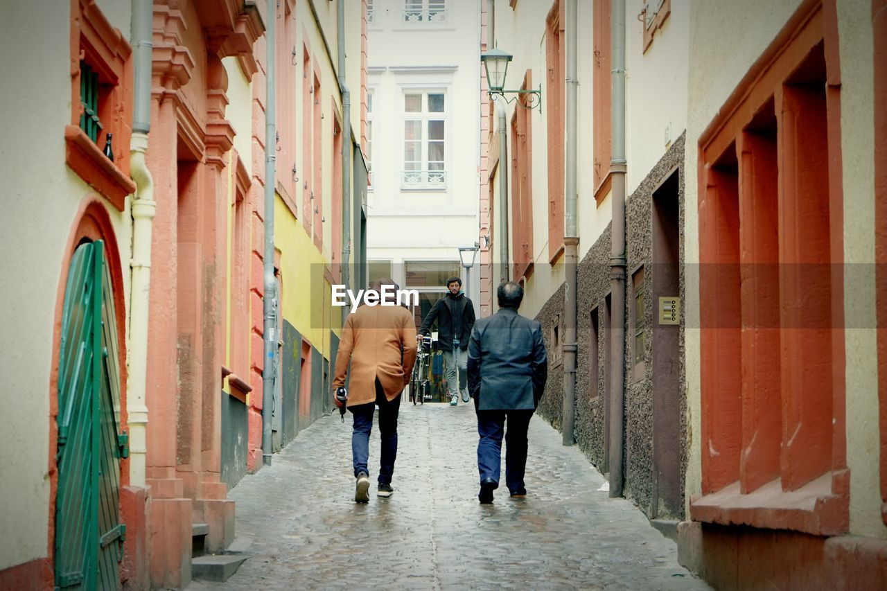 People walking at alley amidst buildings