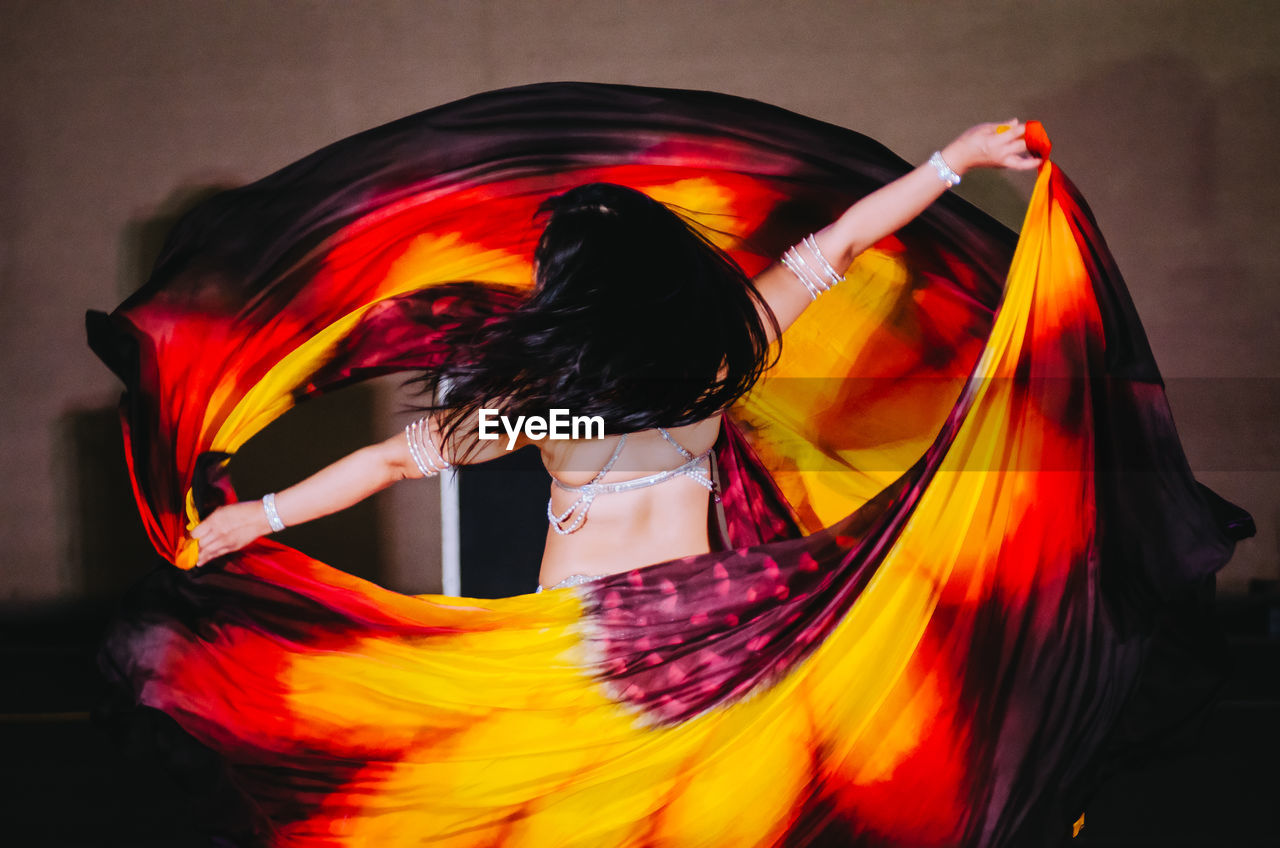 Blurred motion of woman dancing while holding dress performing on stage