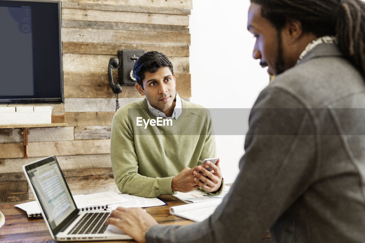 Businessman using laptop while working with colleague at office