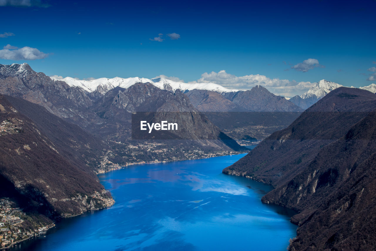 High angle view of lake and mountains against blue sky