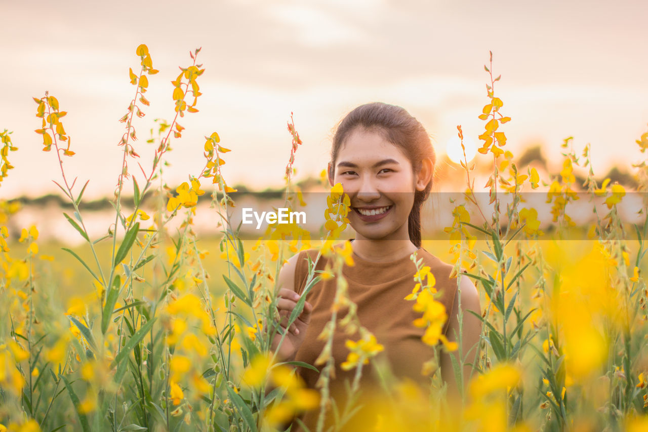 Portrait of smiling young woman standing on field