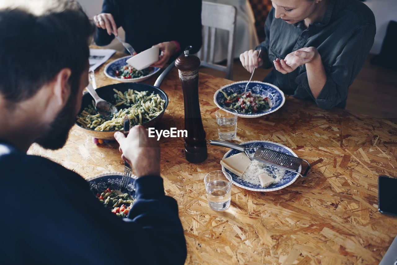 High angle view of couple eating pasta with female friend at home