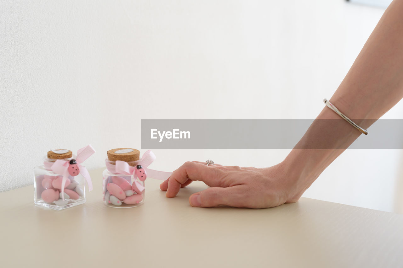 Cropped hand of woman by candies in jars over table