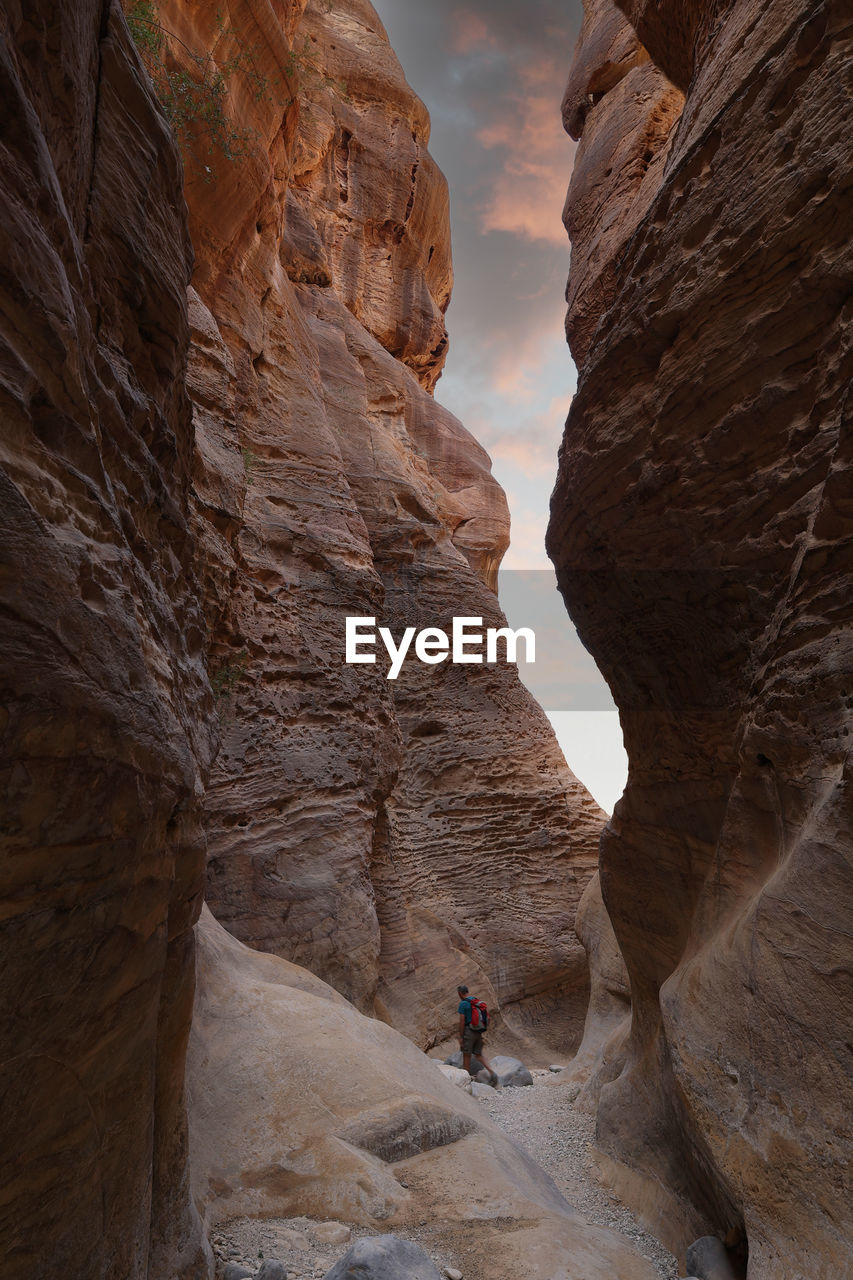 Hiker with backpack walking on wadi ghuweir canyon in dana natural reserve, jordan