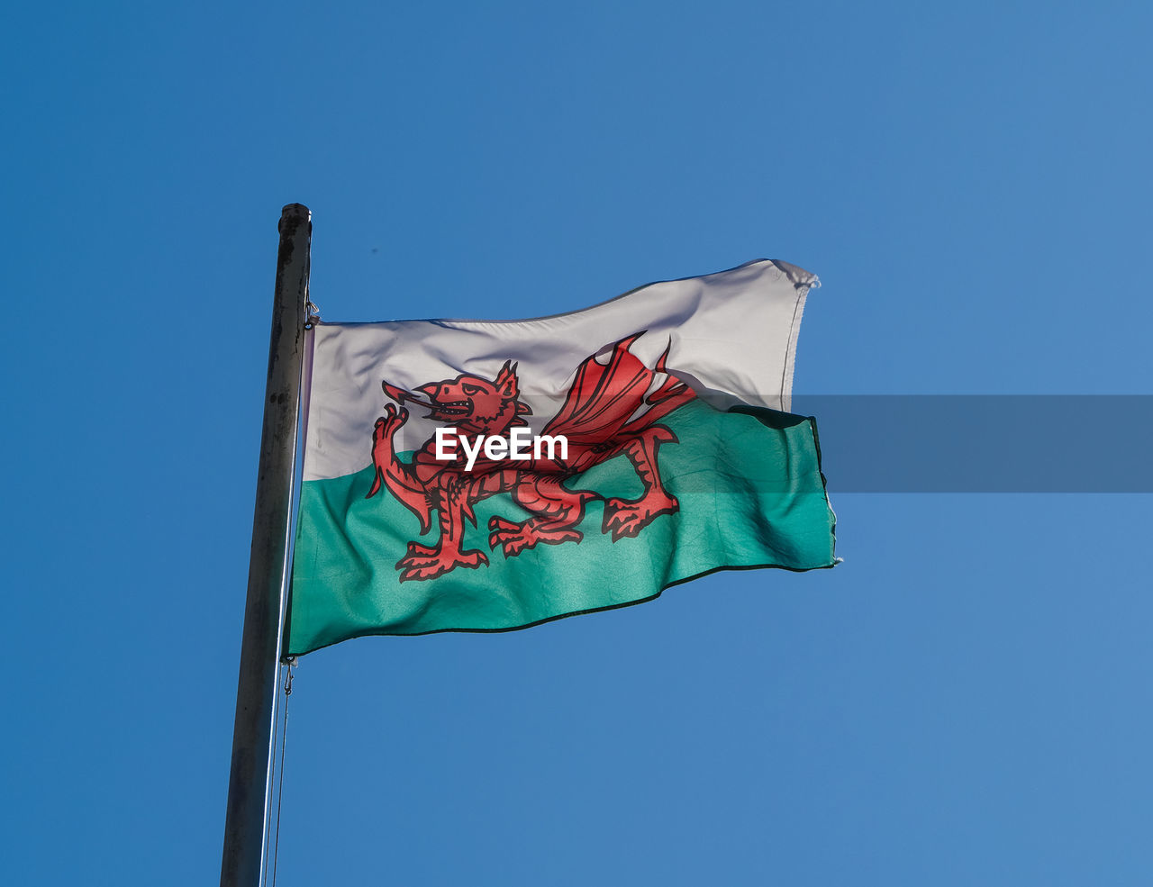 Low angle view of welsh flag against clear blue sky