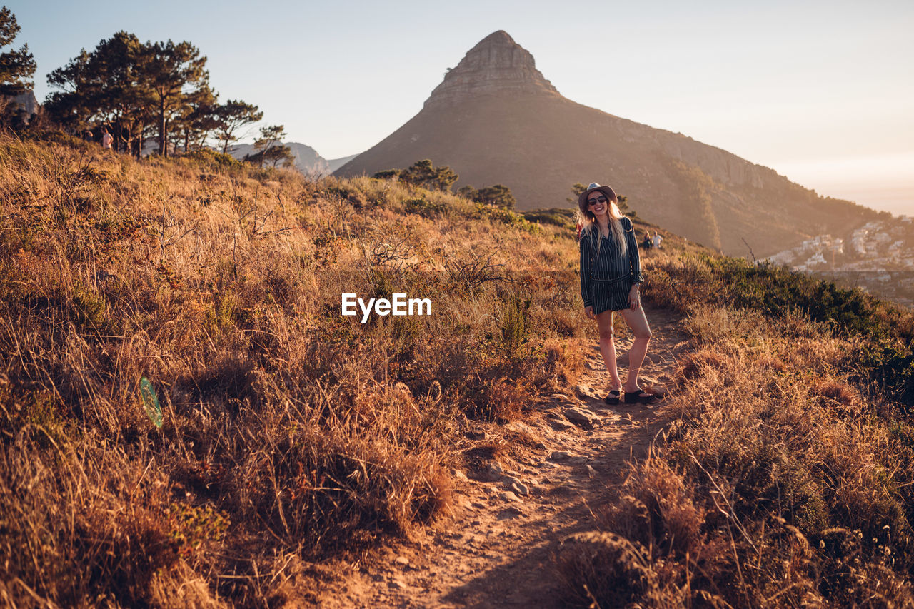 Woman sitting on mountain against sky during sunset
