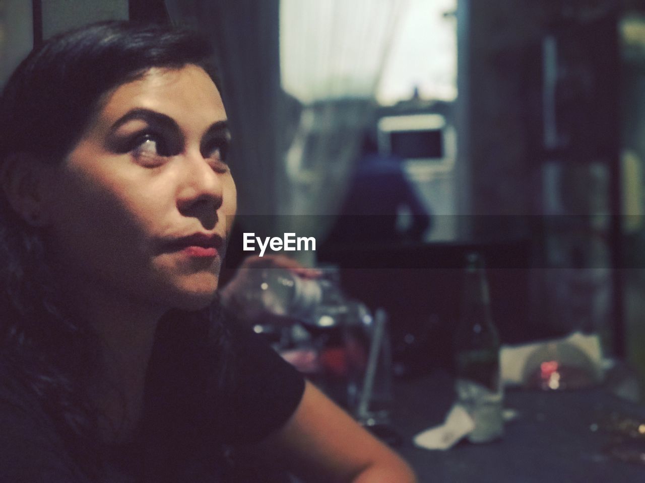 PORTRAIT OF YOUNG WOMAN IN DRINKING GLASS