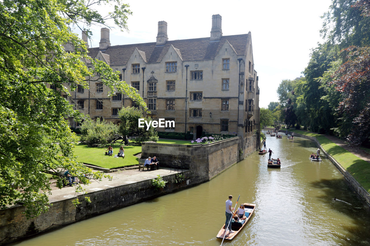 PEOPLE ON RIVER BY BUILDINGS